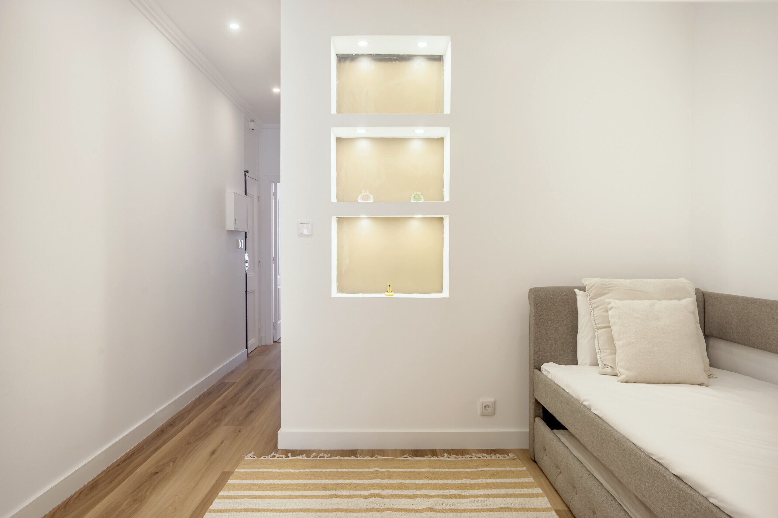 Una camera da letto con un letto, una lampada a parete e un pavimento in legno.