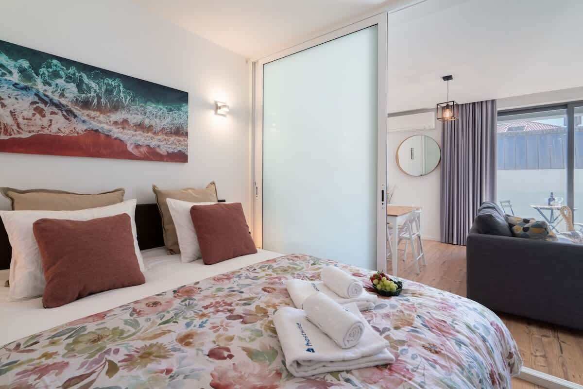 Ein Hotelzimmer mit Bett, einem Bild, einem Schreibtisch und Blick ins Freie.