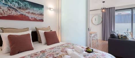 Ein Hotelzimmer mit Bett, einem Bild, einem Schreibtisch und Blick ins Freie.