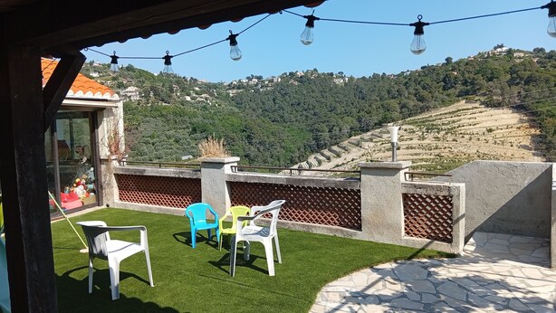 Um pátio externo com cadeiras e vista para uma paisagem montanhosa.