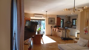 Uma sala moderna com sofá, área de jantar com mesa e cadeiras, cozinha com fogão e armários, e uma janela grande.