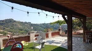 Um pátio ao ar livre com grama sintética, área de estar, espaço infantil e vista para uma paisagem montanhosa.