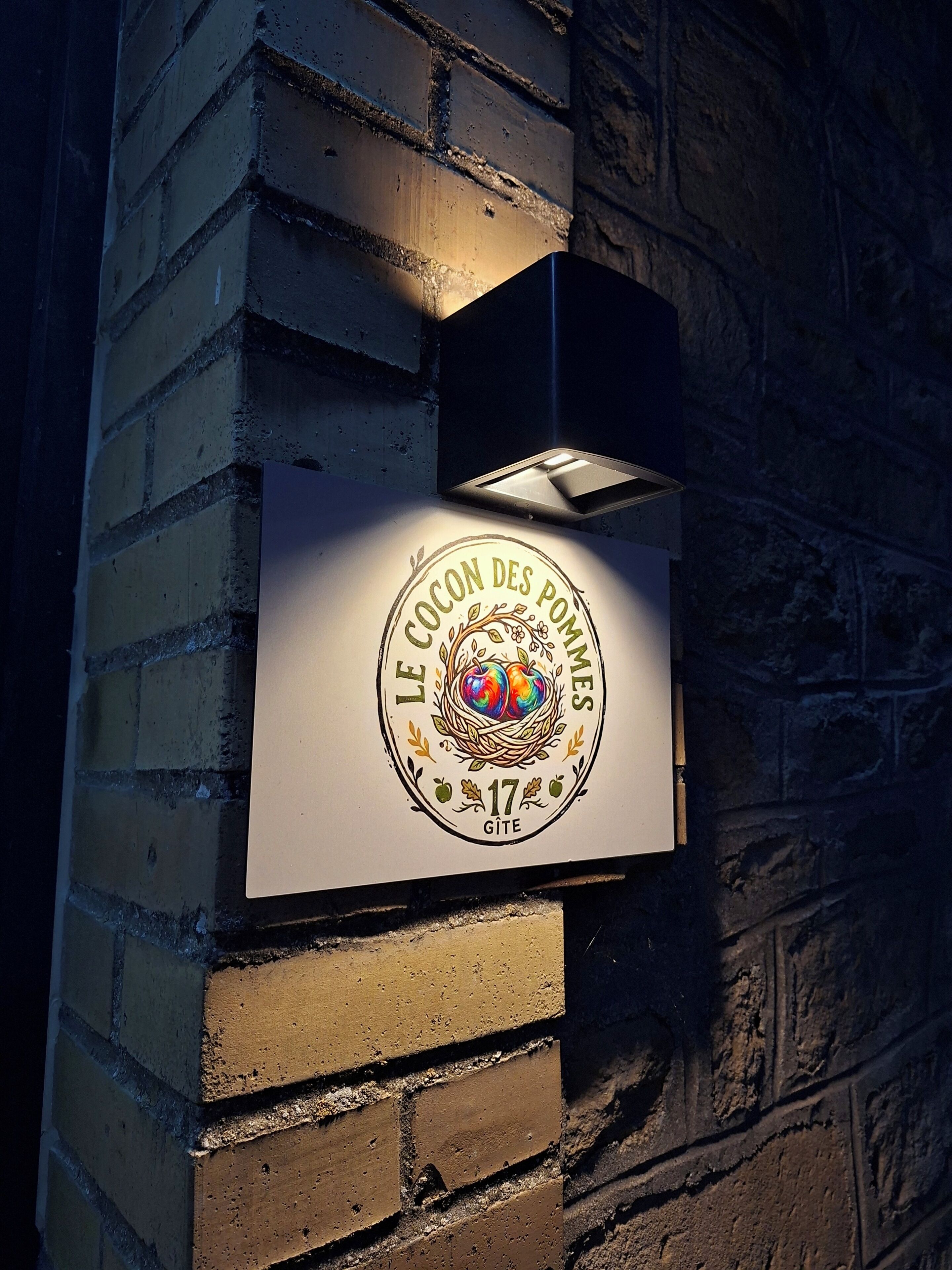 A wall-mounted sign with a logo and text, illuminated by a light fixture.