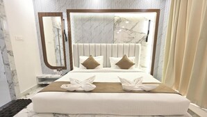Ein Hotelzimmer mit einem Bett, einem großen Spiegel, einem Marmorkopfende und einem Fenster mit Vorhängen.