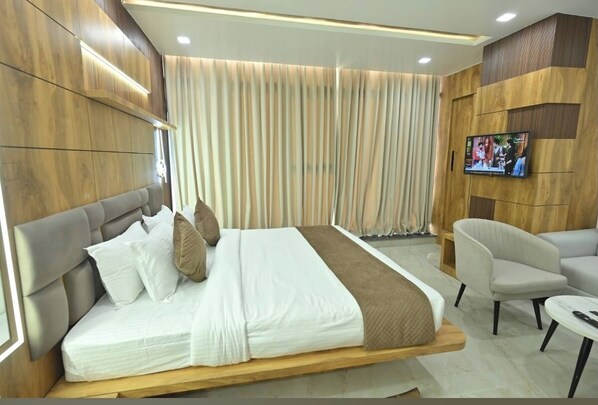 A modern hotel room with a bed, a TV, a chair, and a small table.