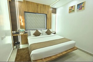 Una habitación de hotel moderna con cama, mesita de noche y un ventanal grande.