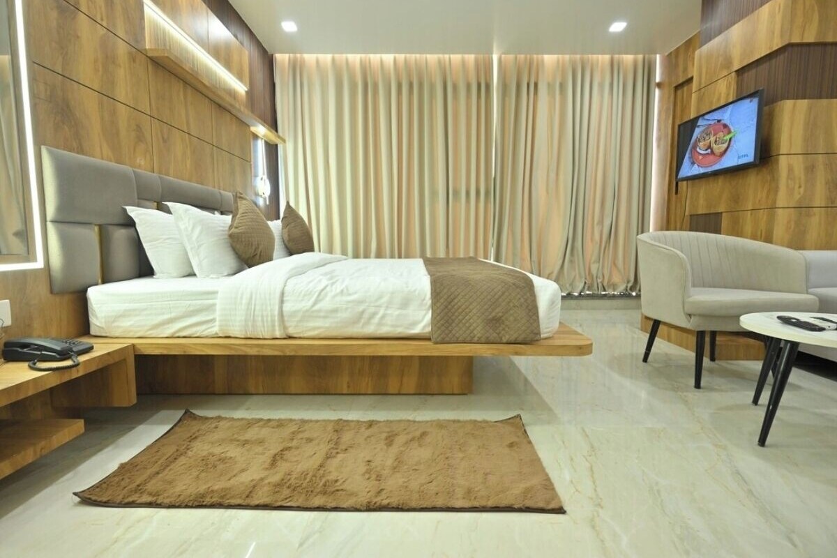 Un dormitorio moderno con cama, mesita de noche y televisor montado en la pared.