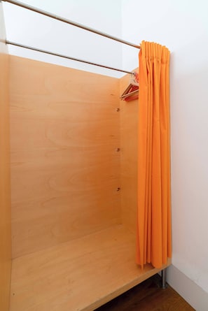 A wooden closet with a metal rod and an orange curtain. - Porto Lounge Hostel - 8 Private Room | Terrace (Porto)