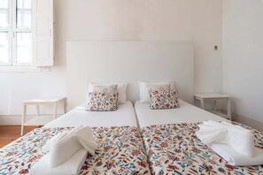A double bed with floral-patterned bedding, two pillows, and a small bedside table. - Porto Lounge Hostel - 8 Private Room | Terrace (Porto)