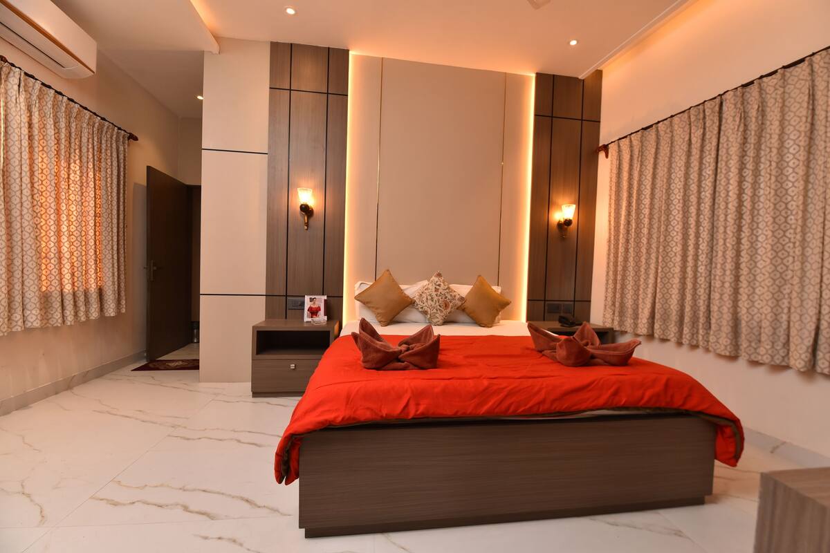 A modern bedroom with a large bed, bedside tables, wall sconces, and curtains.