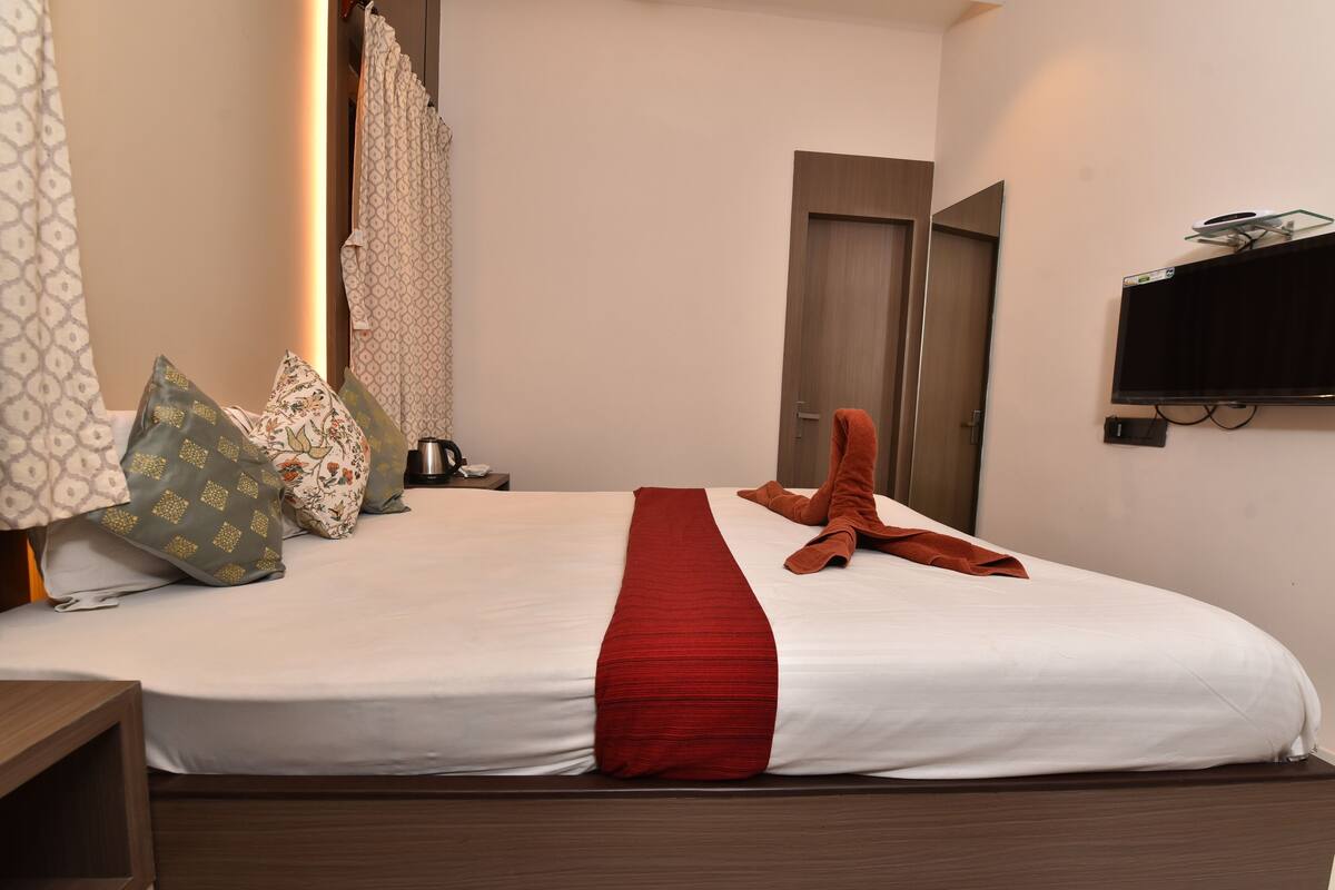 A hotel room with a bed, a TV mounted on the wall, and a door.