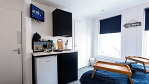 A compact kitchen with a fridge, microwave, and sink, a small TV, and a window with a view. - Guestz at The Wellington (Blackpool)