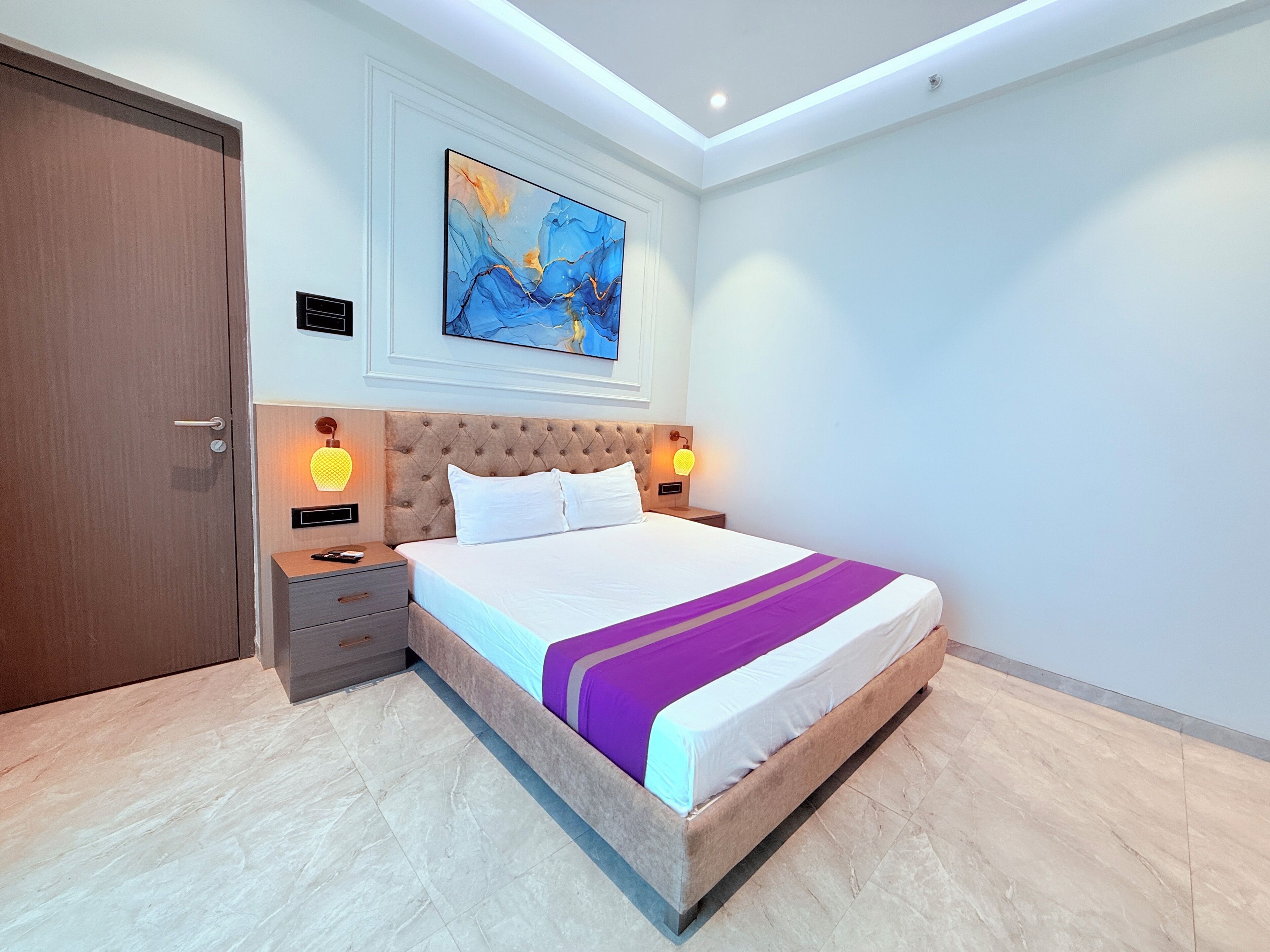 Une chambre moderne avec un grand lit, une table de chevet, un tableau accroché au mur et une porte.