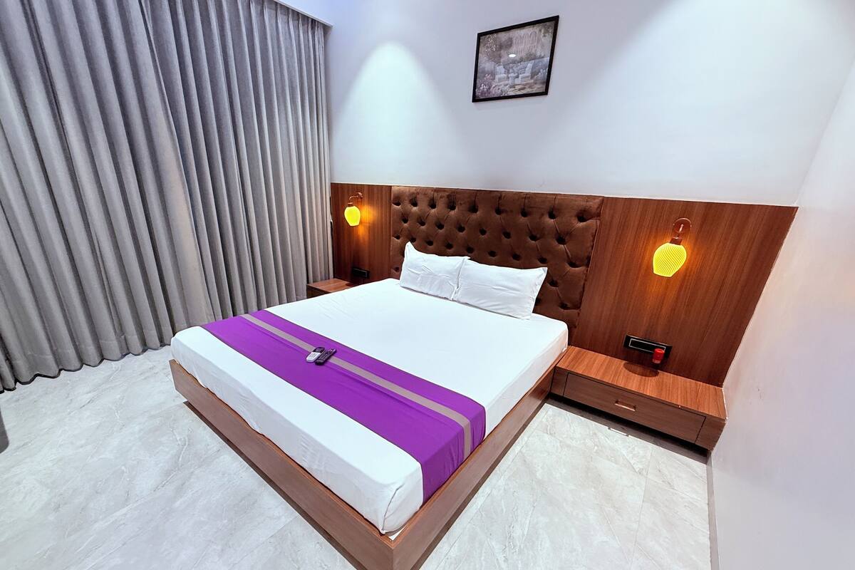 A hotel room with a large bed, a wooden headboard, two bedside tables, and a picture on the wall.