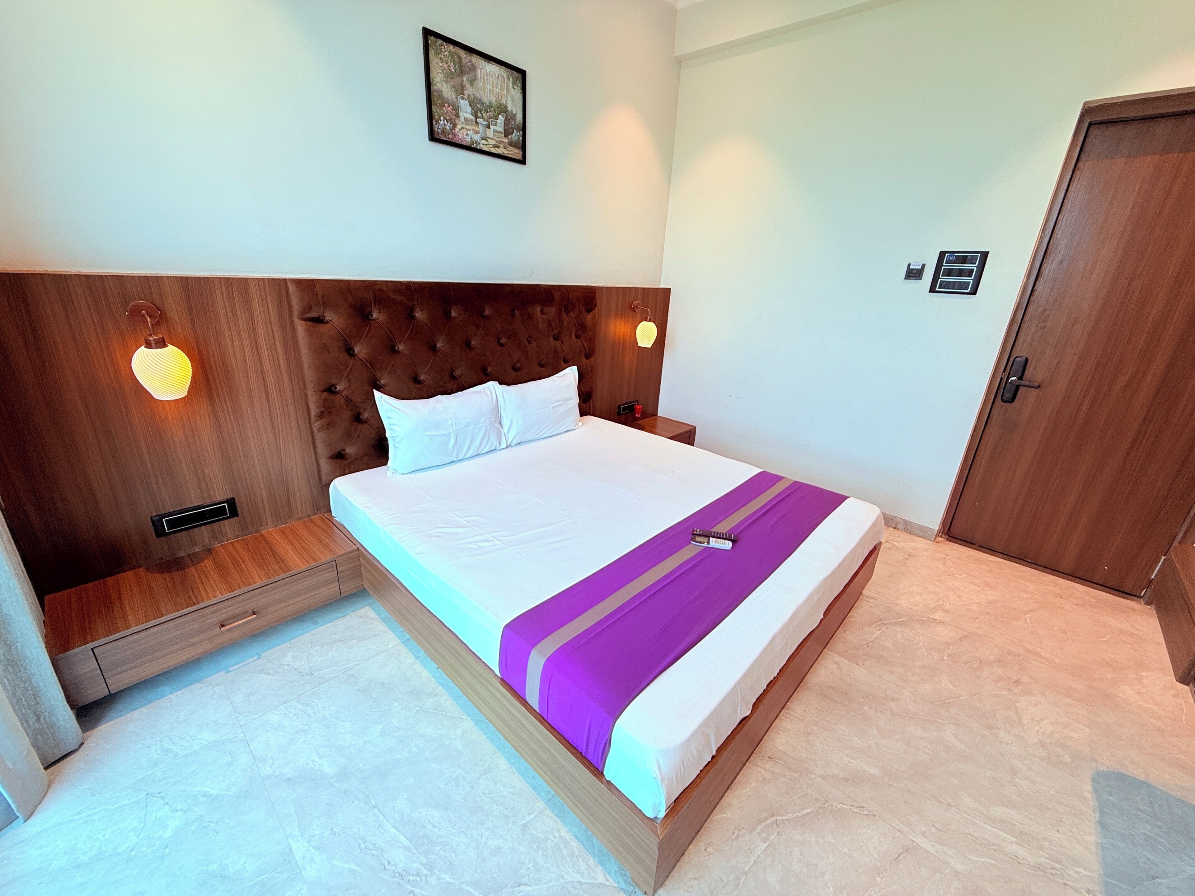 A neatly made bed with a headboard, a bedside table, and a wall-mounted light fixture.