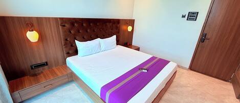 A neatly made bed with a headboard, a bedside table, and a wall-mounted light fixture.