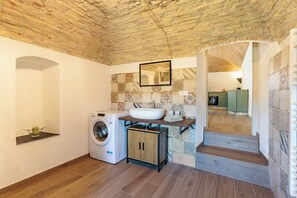 Eine kompakte Küche mit Waschmaschine, Spüle und Spiegel an der Wand.