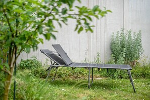 A garden with a metal chair and a laptop on a table.