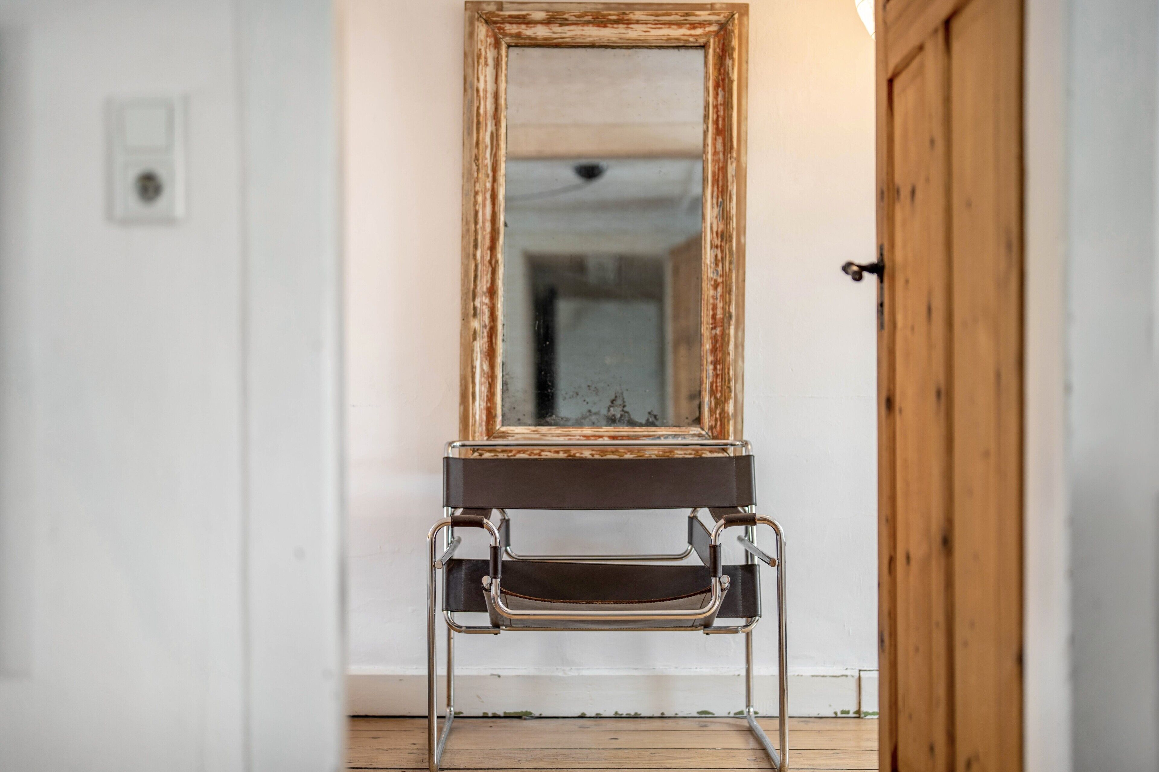 A bathroom with a wooden door, a mirror with a rustic frame, and a metal sink with a black basin.