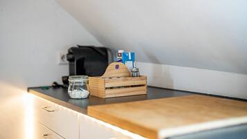 Una kitchenette con una tabla de cortar de madera, un tarro de vidrio y una caja de madera con una botella.