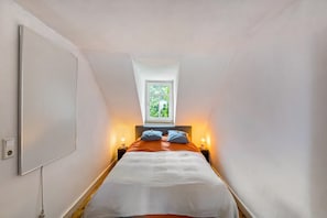 A narrow room with a bed, a window, and wall-mounted lights. - Spacious 60 m² Apartment with Shared Garden & Wi-Fi in Emmendingen (Emmendingen)