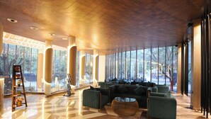 Eine geräumige Lobby mit einem geometrischen Fußbodenmuster, großen Fenstern und einer Sitzecke mit Sofas und einem runden Tisch.
