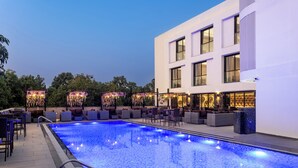 Ein modernes Hotel mit Schwimmbad, Außenbereich und einer gut beleuchteten Fassade.