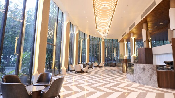 Eine großzügige Lobby mit großen Fenstern, einem Marmorboden und modernen Leuchten.