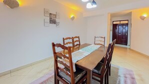 Una zona de menjador amb una taula de fusta, cadires i llums penjades a la paret.