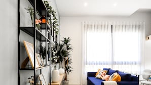 A modern living room with a blue sofa, a black shelving unit, and a large window with sheer curtains. - AS EXT Fgrl Rferial 4 (Fuengirola)