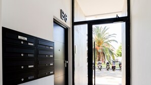 A hallway with a black door marked 'B6', a set of black mailboxes, and a view of parked scooters outside. - AS EXT Fgrl Rferial 4 (Fuengirola)