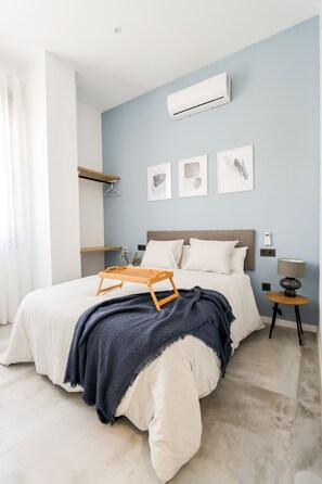 Ein Schlafzimmer mit Bett, Nachttischen, einer Klimaanlage und Wandbildern.
