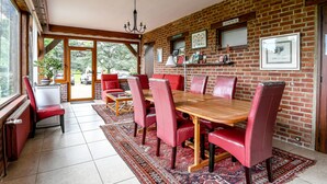 A dining area with a brick wall, a wooden table, red chairs, and a chandelier. - La Bulle Mathusalem Guest Room on the Opal Coast, 8 km from Berck, 15 km from Le Touquet (Verton)