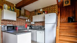 A compact kitchen with a microwave, toaster, and dishwasher, a refrigerator, and a brick wall with a clock and decorative items. - La Bulle Mathusalem Guest Room on the Opal Coast, 8 km from Berck, 15 km from Le Touquet (Verton)