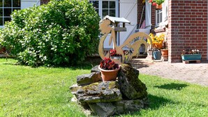 A garden with a decorative metal sculpture, a brick building, and potted plants. - La Bulle Mathusalem Guest Room on the Opal Coast, 8 km from Berck, 15 km from Le Touquet (Verton)