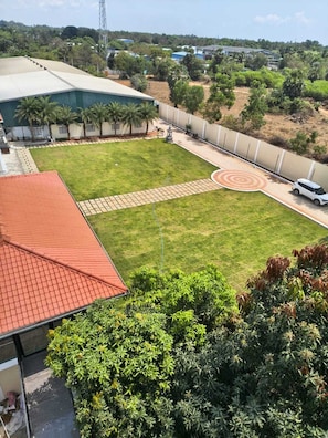 A large, open courtyard with a paved area, surrounded by greenery and buildings.