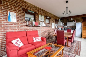 A living room with a red sofa, a glass coffee table, and a dining area with red chairs. - La Bulle Nabuchodonosor B&B on the Opal Coast, 8 km from Berck, 15 km from Le Touquet (Verton)