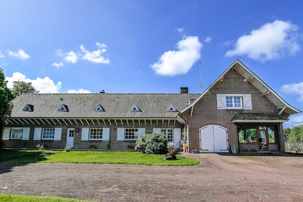 A brick building with a tiled roof, a covered porch, and a paved driveway.