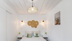 Ein Schlafzimmer mit Bett, Nachttischen, einer Hängeleuchte, Wandleuchten und einem Wandbild.