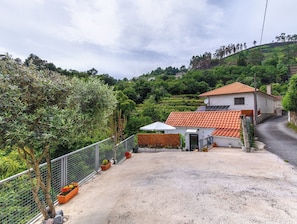 A residential property with a fenced garden, a small house with a tiled roof, and a gravel driveway.