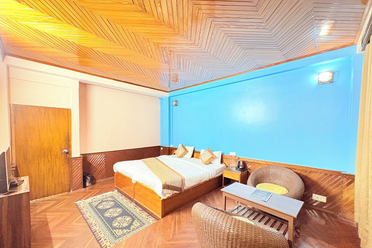 A room with a bed, a nightstand, a chair, a desk, and a blue wall.