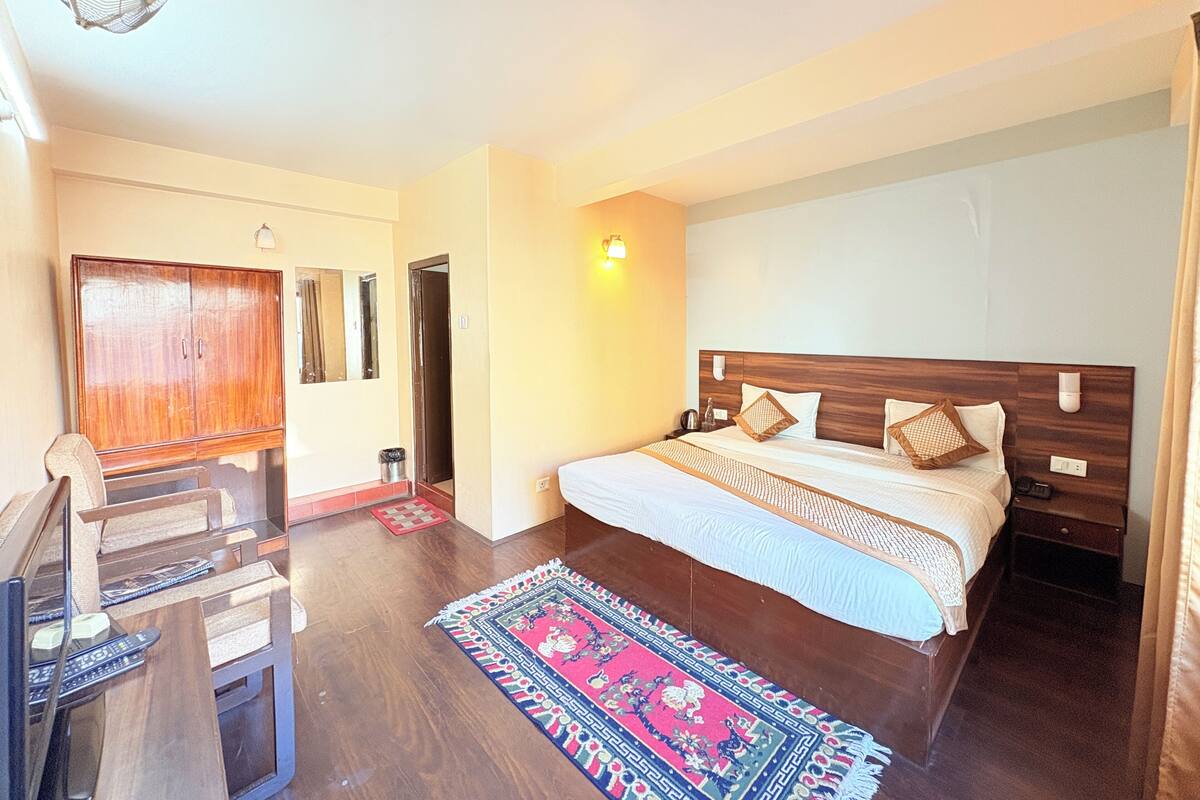 A bedroom with a wooden bed, a nightstand, a desk, and a chair.