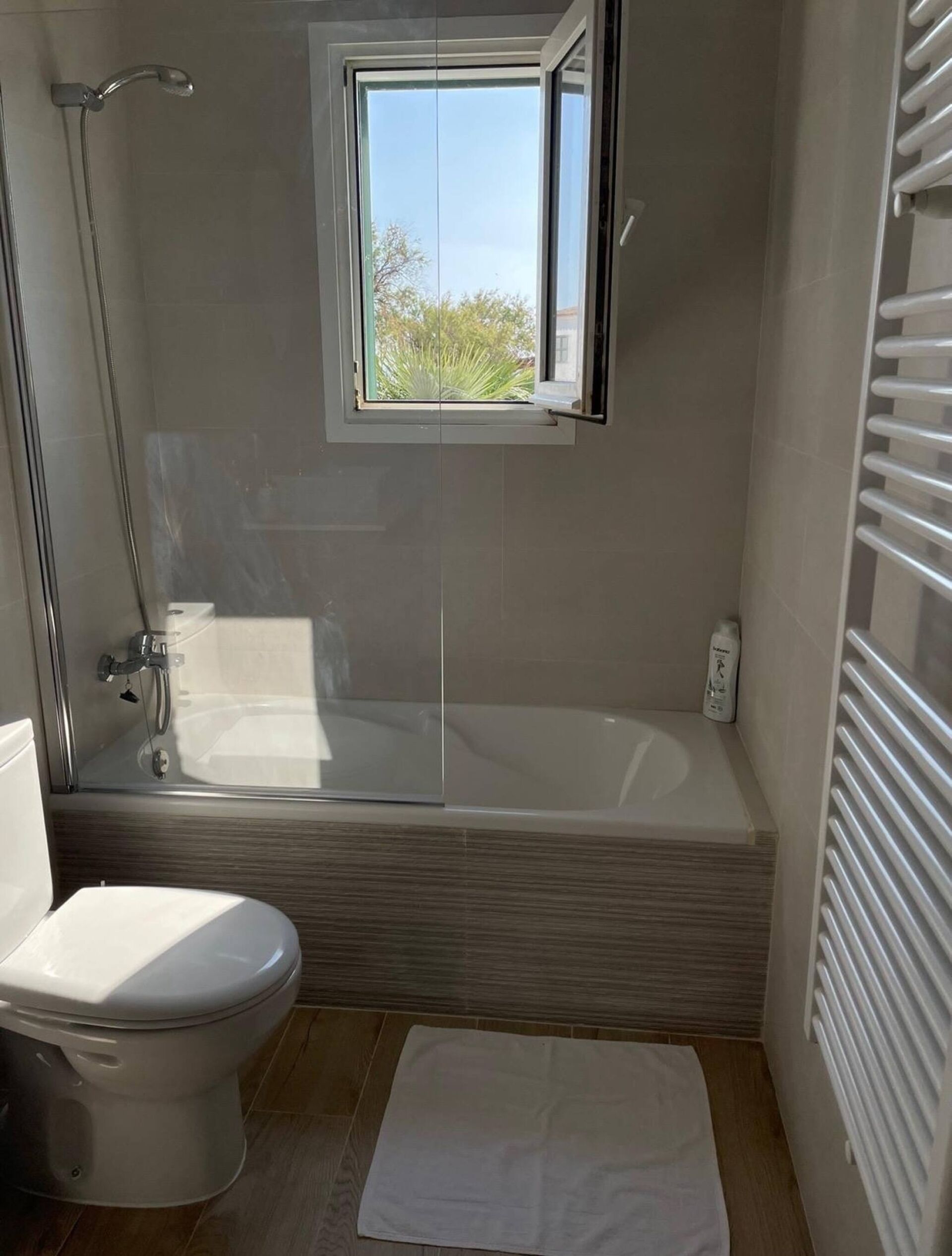 Une salle de bain avec une baignoire, des toilettes et une fenêtre.