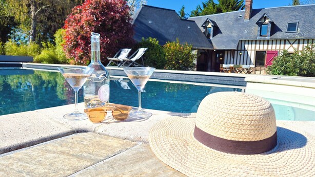 Une scène de bord de piscine avec un chapeau, des lunettes de soleil et deux verres à martini.