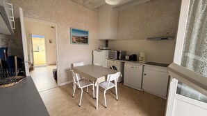 A compact kitchen with a dining table, chairs, a microwave, a coffee maker, and a washing machine. - Apartment in Soulac town center, all on foot (Soulac-sur-Mer)