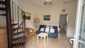 A room with a staircase, a sofa, a small table, and a chair. - Apartment in Soulac town center, all on foot (Soulac-sur-Mer)