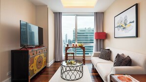 Ein modernes Wohnzimmer mit Flachbildfernseher, einem farbenfrohen Schrank, einem runden Couchtisch, einem weißen Sofa und einem großen Fenster mit Blick auf die Stadt.