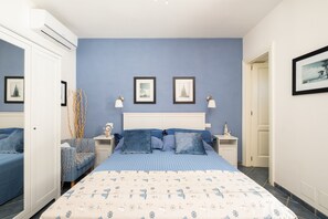 Ein Schlafzimmer mit einem Bett, zwei Nachttischen, einem kleinen Tisch, einem Stuhl und einer Tür.