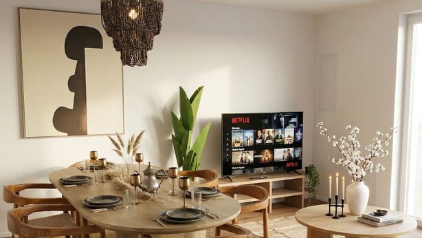 Ruokailutilassa on puinen pöytä, johon on katettu kuudelle, ja sen ympärillä on tuoleja. Lisäksi tilassa on televisio, jossa näkyy Netflix, sekä koristeellinen maljakko, jossa on kukkia.