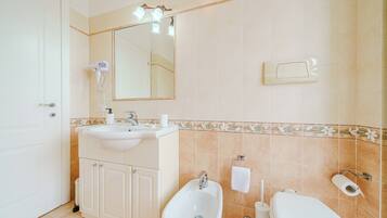 Ein Badezimmer mit Waschbecken, Bidet, Toilette und Spiegel.